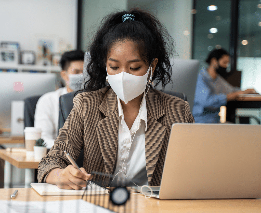 Woman wearing mask, working on computer in office, employing contractor safety